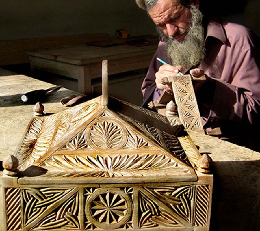A craftsman chip-carving an ornate wooden box in his workshop