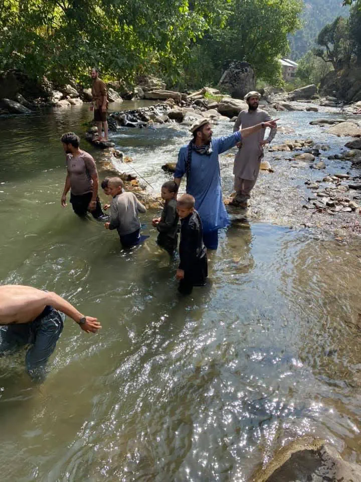 Abdulrahman Chonish fishing with local men and children on the Waygal river, Nuristan