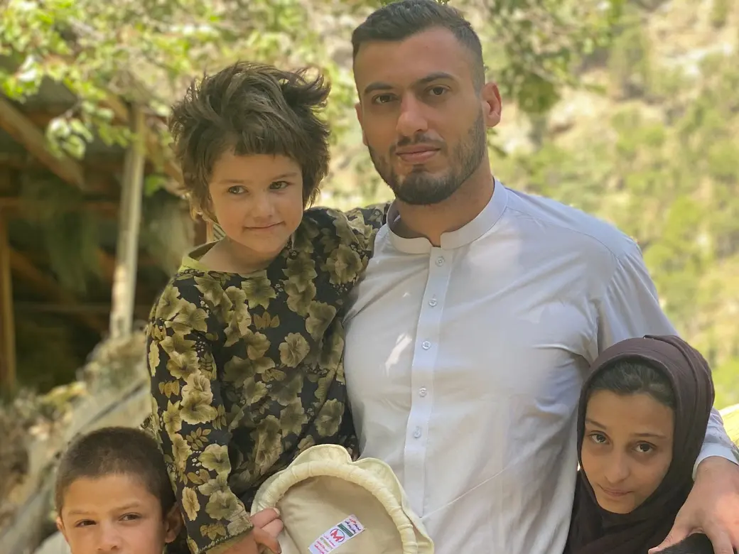 Ahmed Bilal, Nuristani's country representative in the UK, in a white shalwar kameez with children of the Sewketra valley in Waygal district, a small child beside him holding a pakol