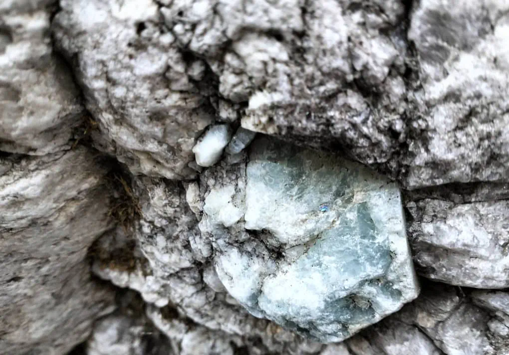 Pale blue-green aquamarine crystals set in grey and white pegmatite rock in the Sewketra valley of Waygal, Nuristan, a gem field not yet worked