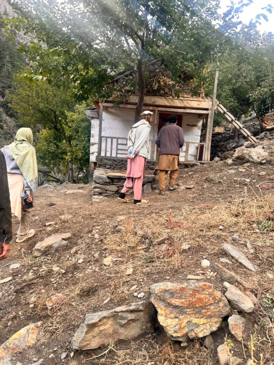 Guests from the Netherlands arriving with their guide at a small whitewashed house with a timber veranda in the Sewketra valley of Waygal