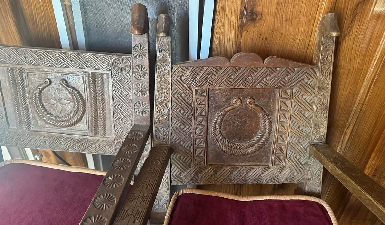 Two carved Nuristani chair backs with a horned crescent motif, rosettes and meander borders