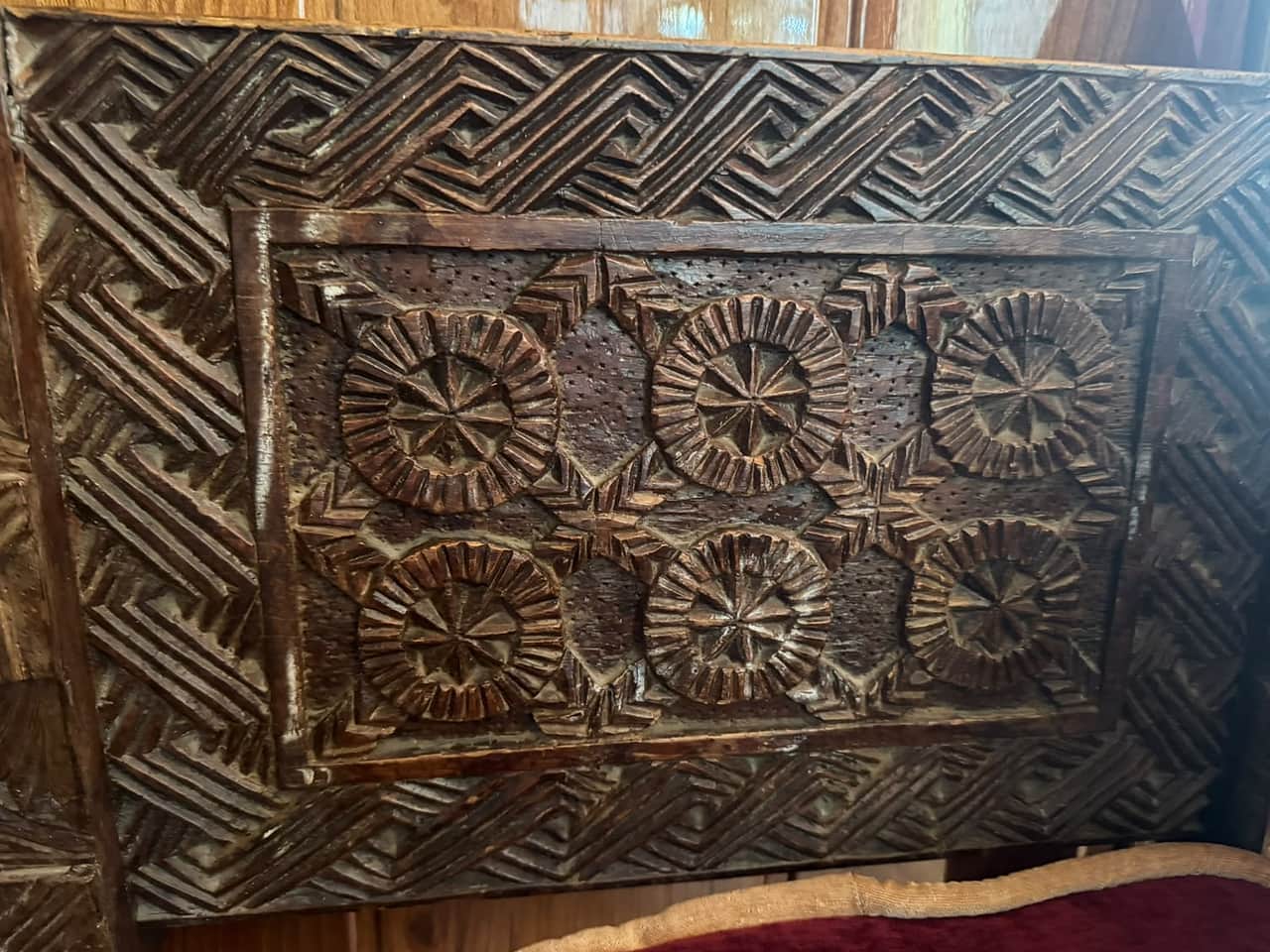 A carved cedar panel from a Nuristani chair, with six sun rosettes inside a border of chevrons