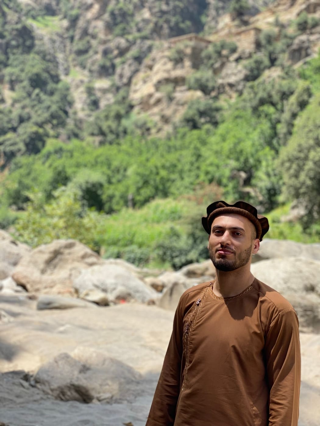 A young Nuristani man in a pakol beside a mountain river