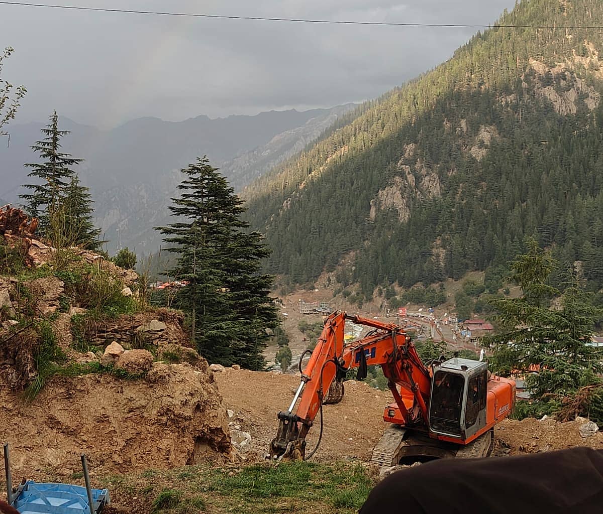 An excavator carrying out rebuilding work on a hillside above Parun, with the valley and village below