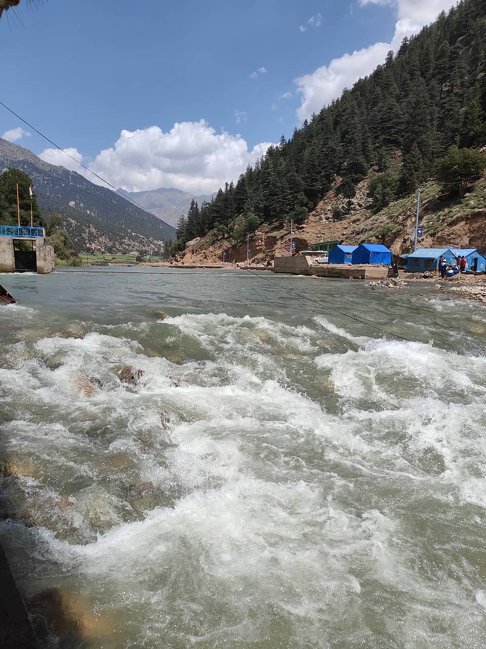 The fast Parun river running past tents and forested slopes in the Parun valley