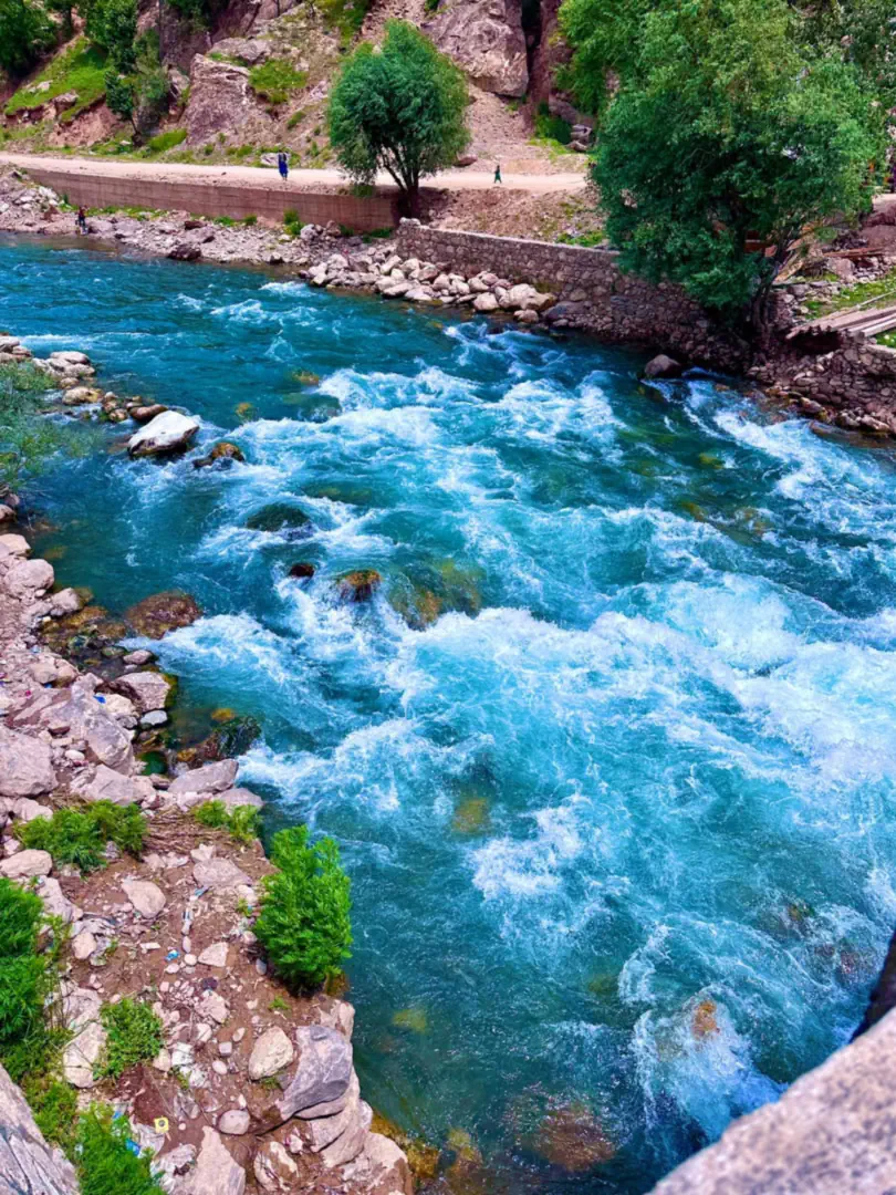 White water on the turquoise Parun river between rocky banks, a walled path above