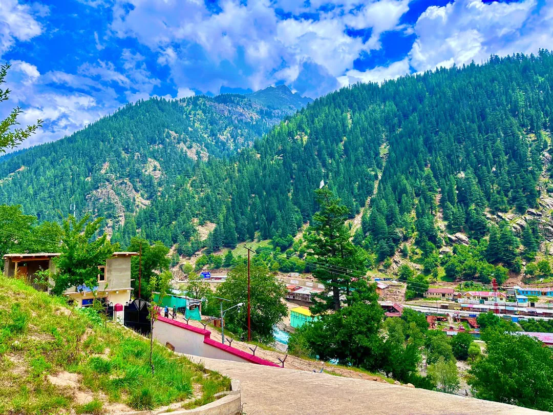 Houses and shops on the valley floor in Parun, the capital of Nuristan, beneath pine-forested mountains