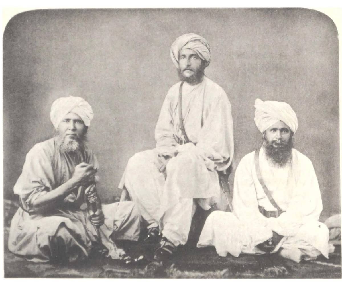 An 1880s studio photograph of William McNair seated between two companions, all three in turbans and loose robes, dressed as they travelled to Kafiristan